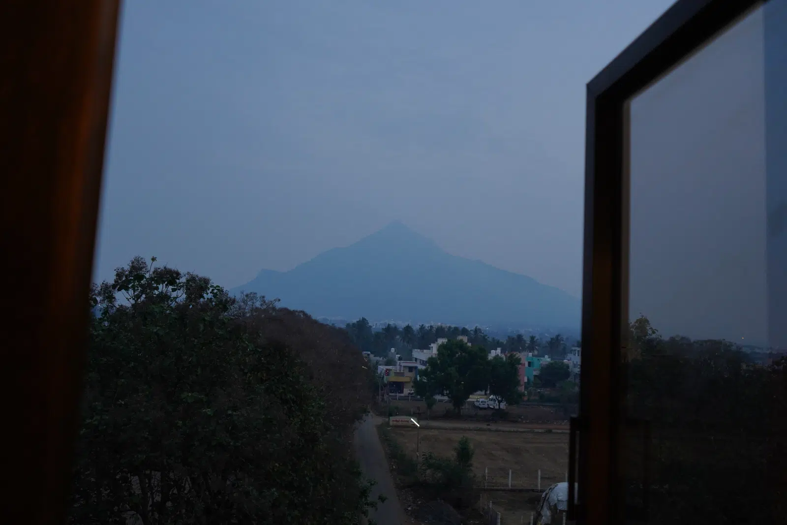 View of Arunachala hill from a front-facing room window at dusk