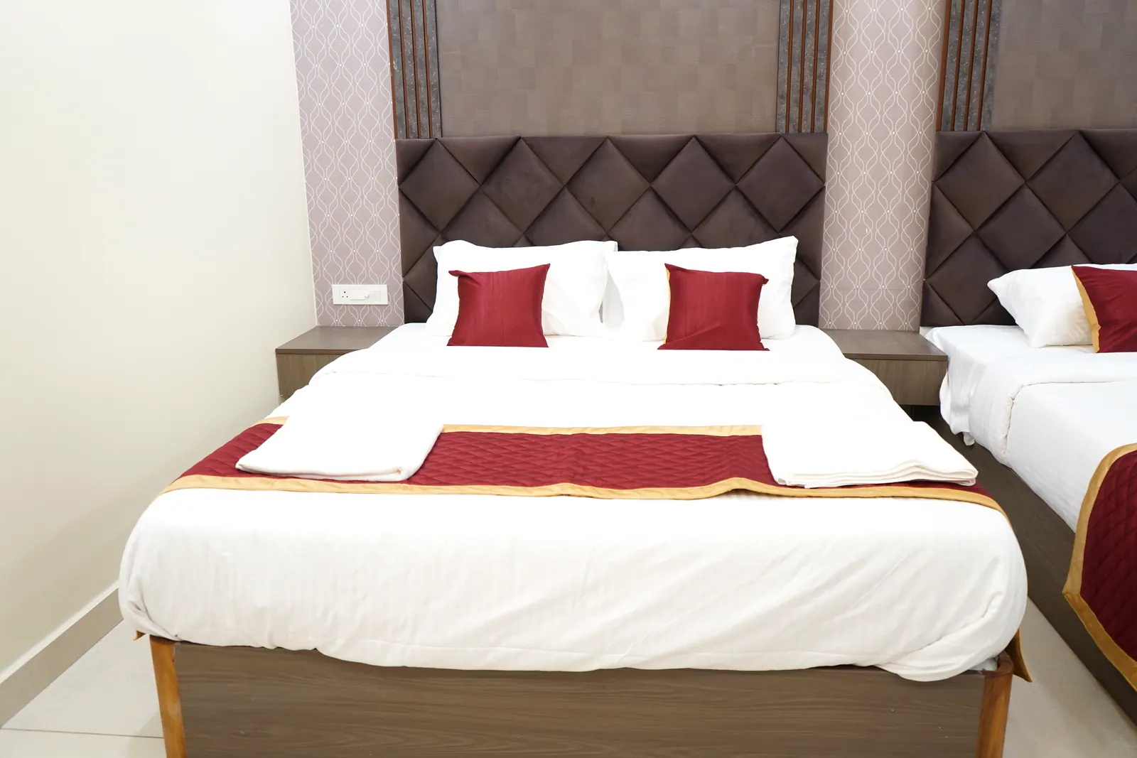 Super Deluxe room queen bed with an upholstered headboard and red and gold bed runner