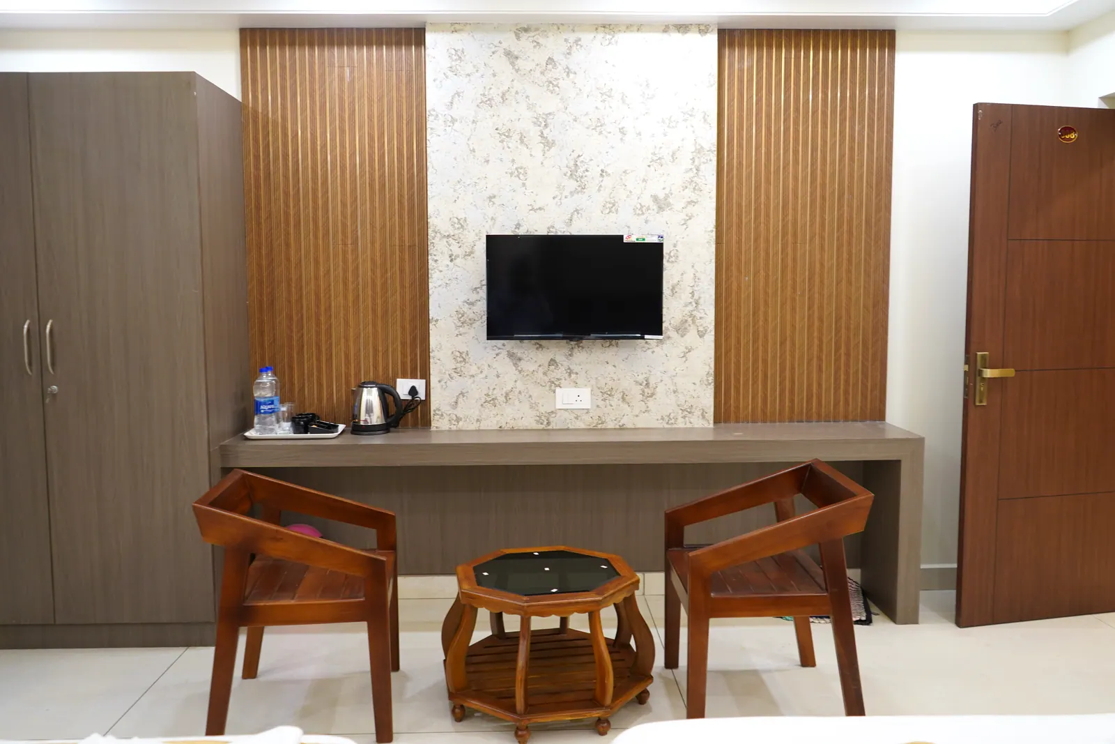 Super Deluxe room with a wall-mounted television, a counter, two armchairs and a wardrobe