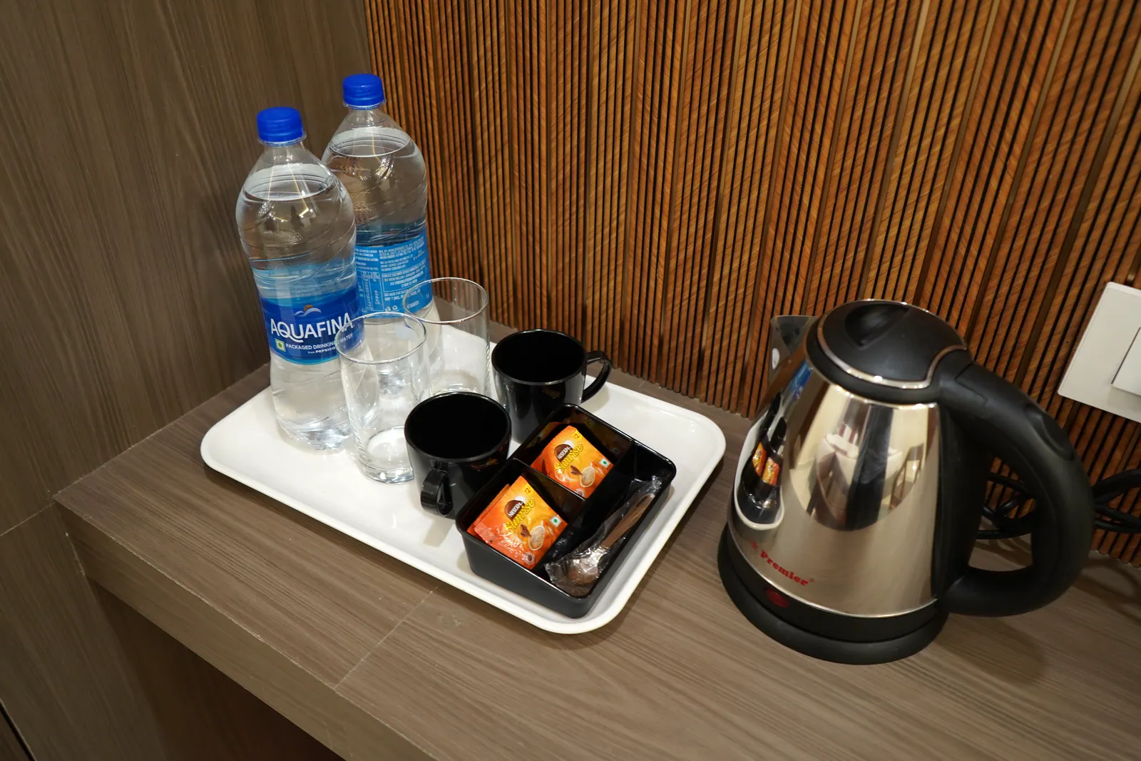 Tray with an electric kettle, cups, tea sachets and bottled drinking water